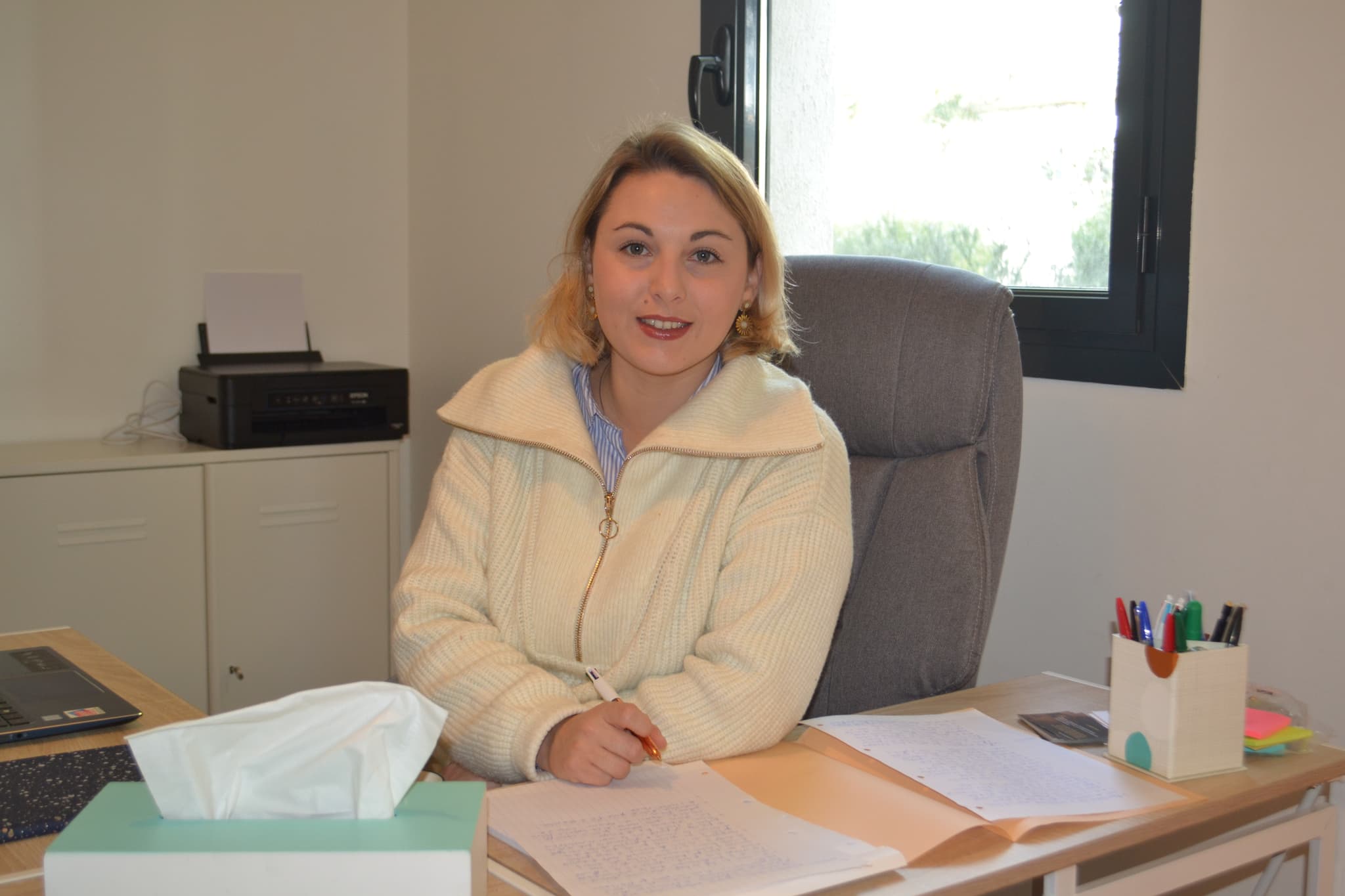 Photo de la psychologue à son bureau faisant un jolie sourire.